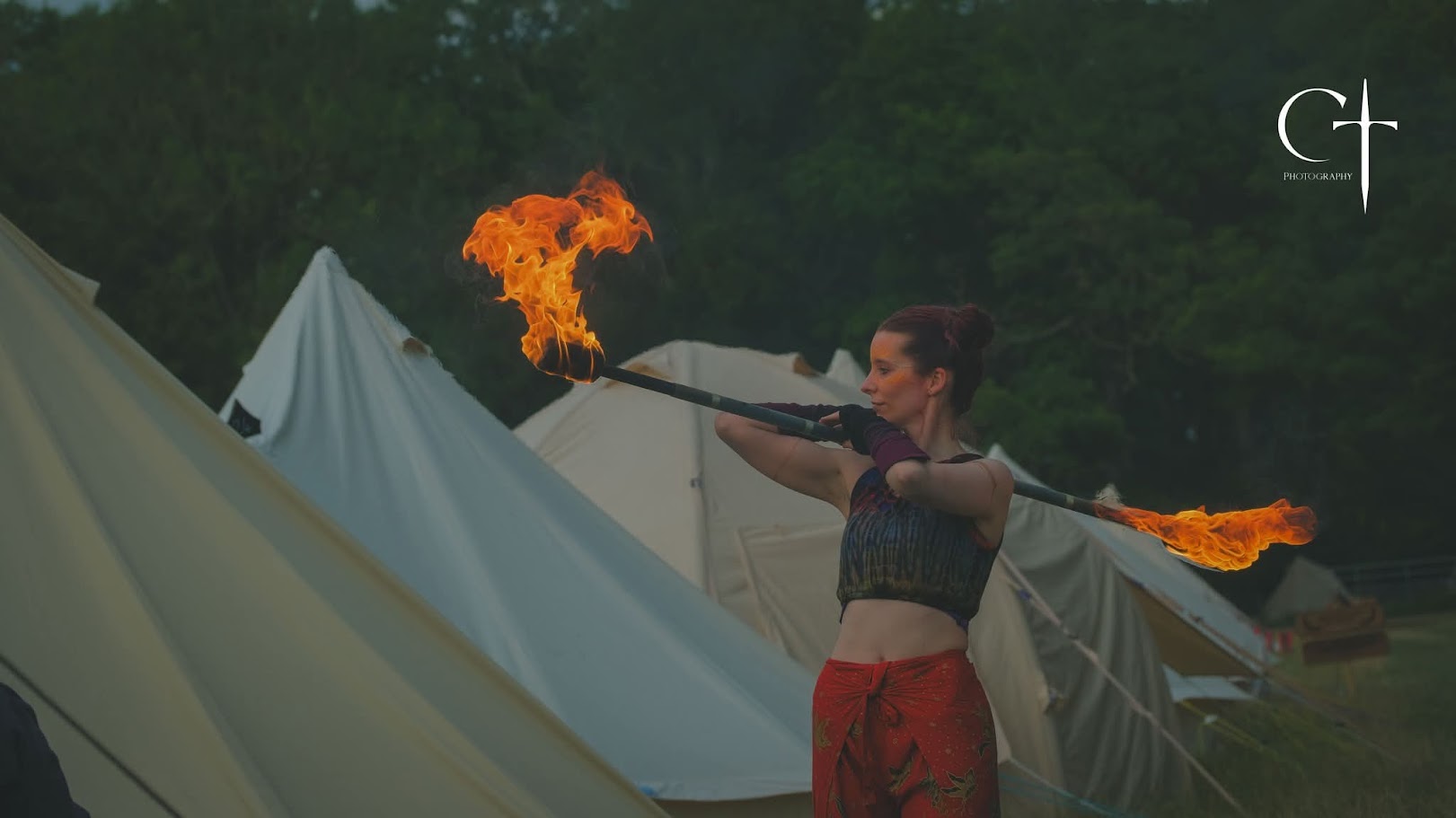 Performer spinning fire in front of the camp tents